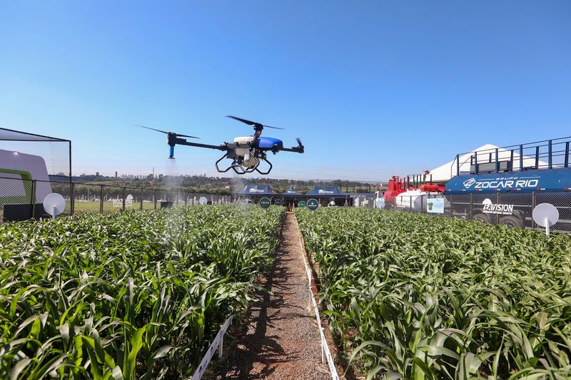 Agricultural drone hovering above rows of crops at an outdoor field demonstration